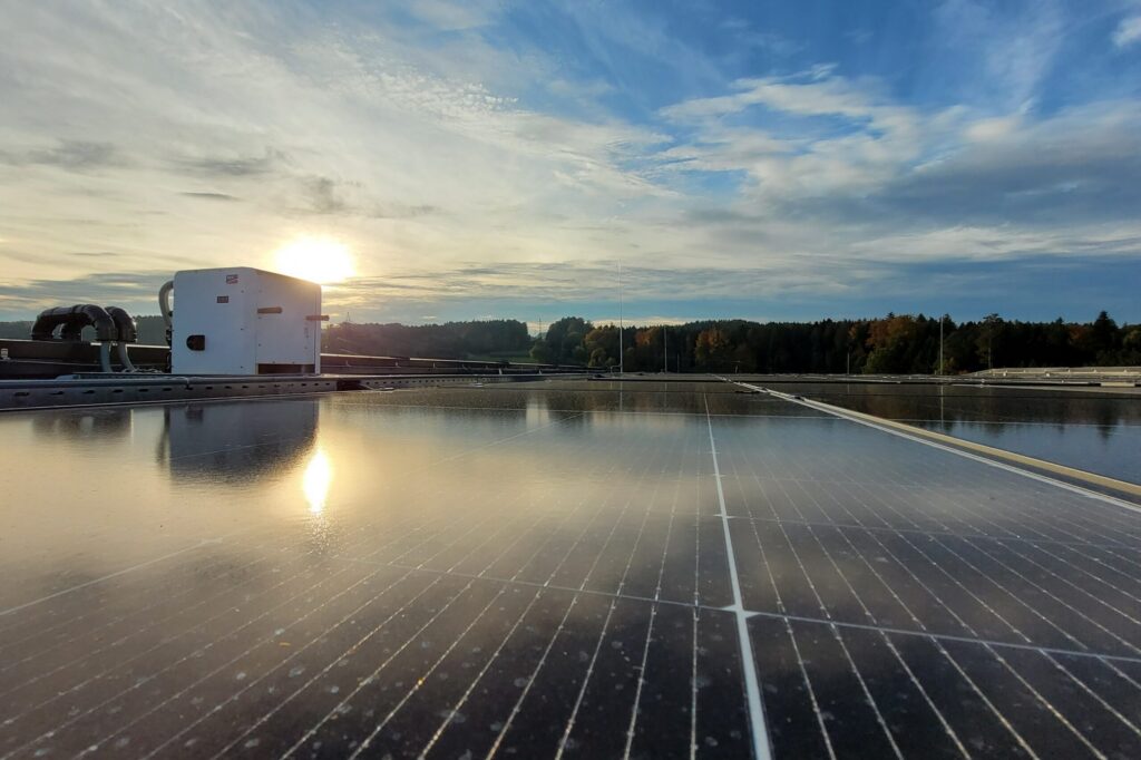 Photovoltaikmodule und Wechselrichter auf einem Flachdach bei tief stehender Sonne